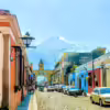 Daytime street scene with Santa Catalina Arch in Antigua Guatemala, with Volcán de Fuego in background