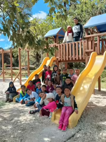 Group of children around the playground equipment of The Little Mountain School in Joya Honda, GT